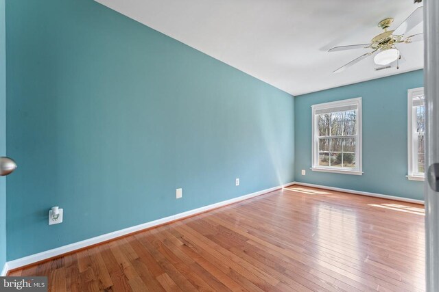 unfurnished room featuring ceiling fan, wood finished floors, and baseboards