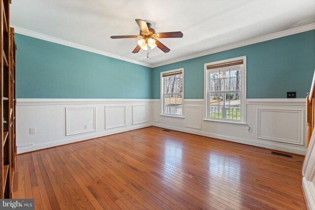 spare room with ceiling fan, a wainscoted wall, hardwood / wood-style flooring, and crown molding