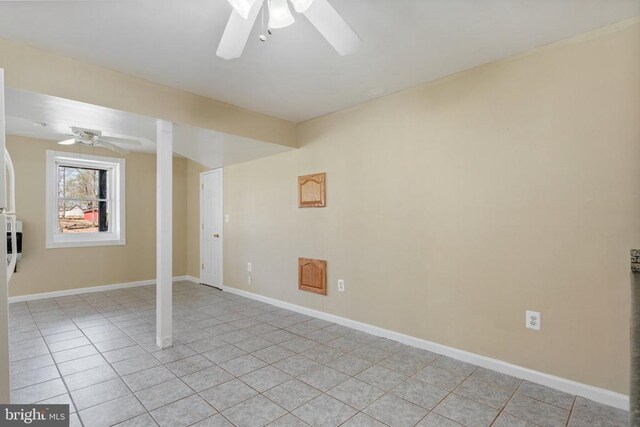 below grade area featuring ceiling fan, light tile patterned flooring, and baseboards