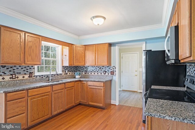 kitchen with a sink, light wood-type flooring, backsplash, ornamental molding, and brown cabinetry