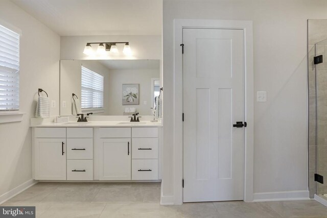 bathroom featuring a sink, double vanity, a stall shower, and baseboards