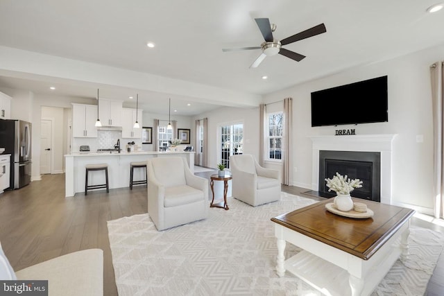 living room with a fireplace with flush hearth, light wood-style floors, ceiling fan, and recessed lighting