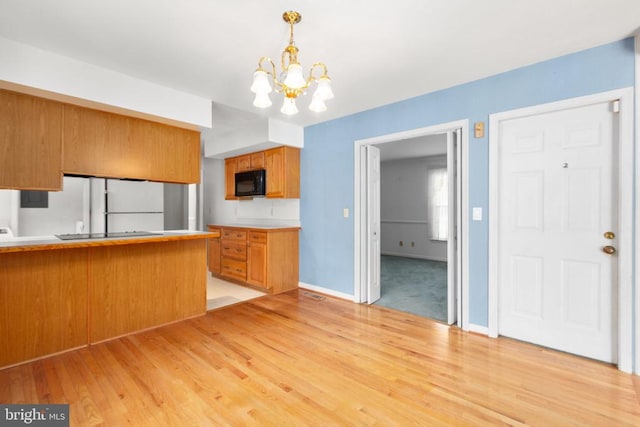 307 Butternut Dr, Fredericksburg, VA 22408 - kitchen featuring a chandelier, light wood-style flooring, black appliances, brown cabinetry, and decorative light fixtures