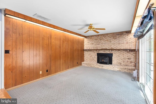 307 Butternut Dr, Fredericksburg, VA 22408 - unfurnished living room with ceiling fan, brick wall, wood walls, carpet floors, and a wood stove