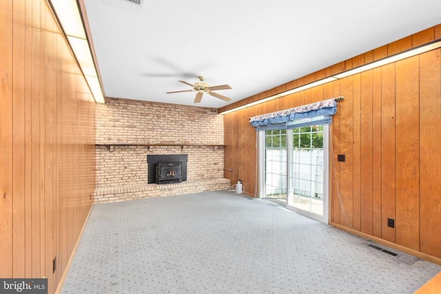 307 Butternut Dr, Fredericksburg, VA 22408 - unfurnished living room with a wood stove, a ceiling fan, wood walls, and carpet floors