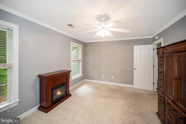 unfurnished living room with baseboards, light colored carpet, a ceiling fan, ornamental molding, and a glass covered fireplace