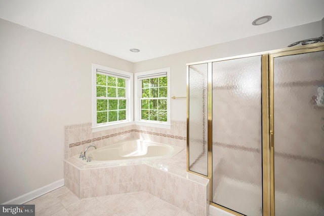 bathroom with a bath, a stall shower, tile patterned flooring, and baseboards