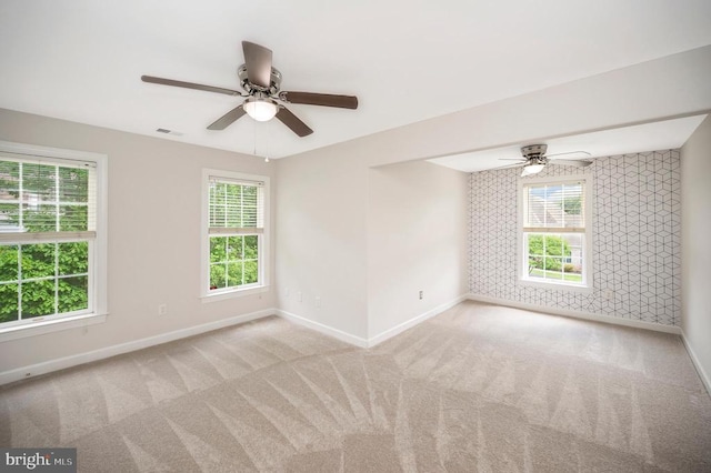 carpeted empty room with baseboards, ceiling fan, and healthy amount of natural light