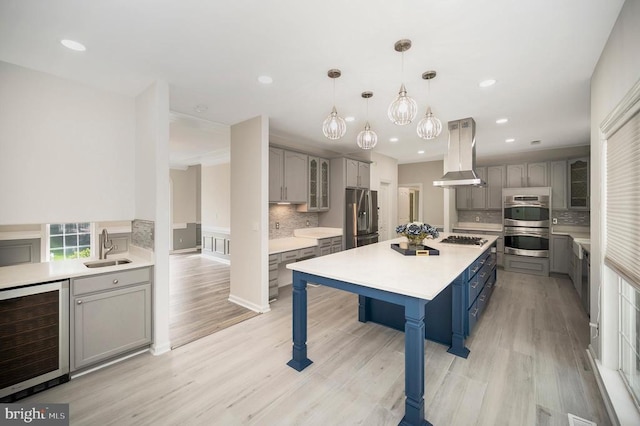 kitchen with wine cooler, island exhaust hood, gray cabinetry, a sink, and decorative backsplash