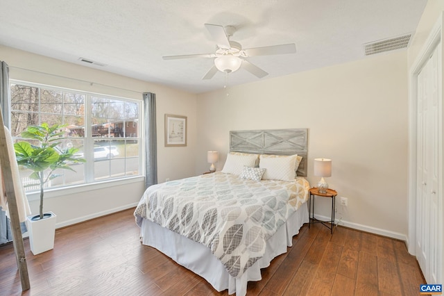 bedroom with a closet, wood finished floors, visible vents, and baseboards