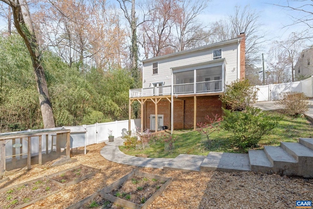 back of property featuring a gate, a chimney, a wooden deck, a garden, and a fenced backyard