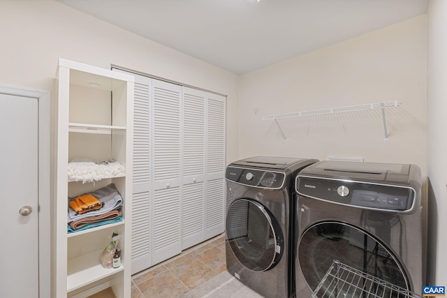 clothes washing area featuring laundry area, washer and clothes dryer, and stone finish flooring