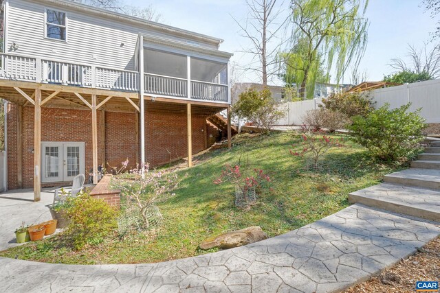 view of yard featuring french doors, a sunroom, a deck, stairway, and a fenced backyard