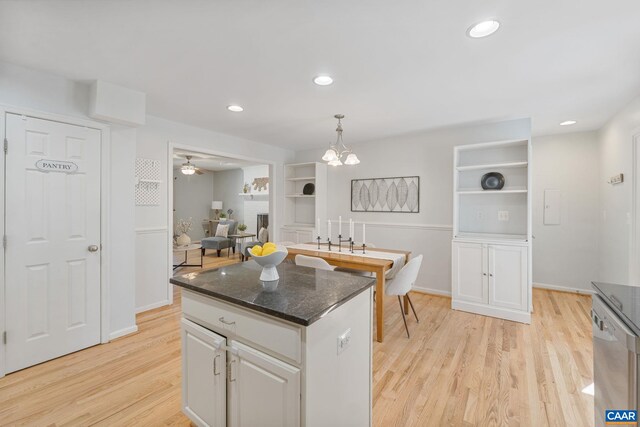 kitchen featuring hanging light fixtures, white cabinetry, stainless steel dishwasher, light wood-style floors, and a kitchen island