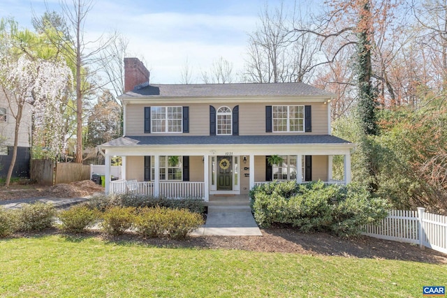 view of front of property with a chimney, a front lawn, covered porch, and fence