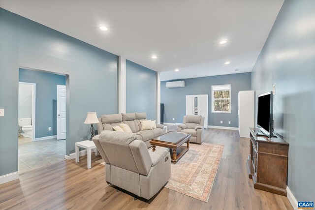 living room with baseboards, recessed lighting, a wall mounted air conditioner, and light wood-type flooring