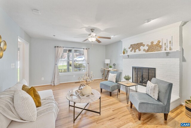 living room with a ceiling fan, baseboards, a fireplace, and light wood-type flooring