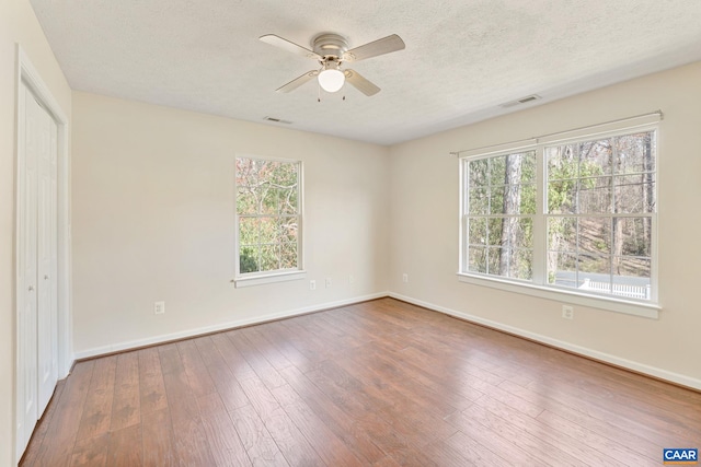 unfurnished bedroom with a textured ceiling, visible vents, baseboards, and wood-type flooring