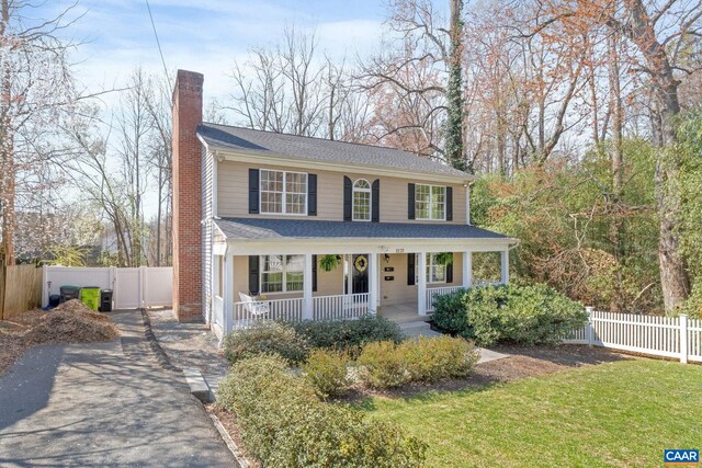 view of front of house with covered porch, roof with shingles, fence, driveway, and a chimney