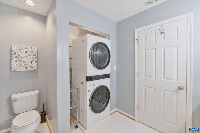 laundry area with laundry area, stacked washer / dryer, visible vents, and baseboards