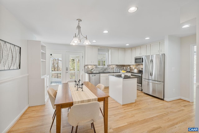 kitchen featuring stainless steel appliances, tasteful backsplash, baseboards, a kitchen island, and dark countertops