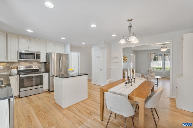 kitchen with dark countertops, appliances with stainless steel finishes, tasteful backsplash, and light wood-type flooring