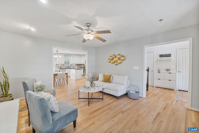 living room featuring light wood finished floors, baseboards, and ceiling fan