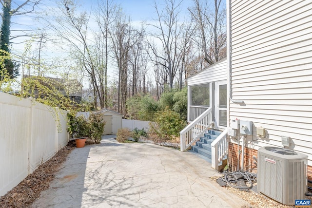 view of patio with central air condition unit, an outdoor structure, a fenced backyard, and a storage unit