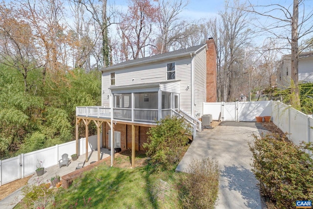 view of front of house with a gate, cooling unit, a chimney, a deck, and a fenced backyard