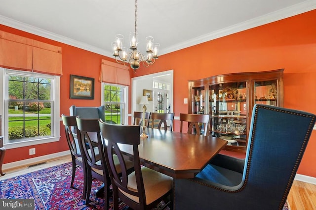 dining space featuring a chandelier, crown molding, wood finished floors, and baseboards
