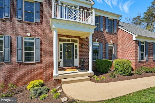 property entrance with a balcony and brick siding