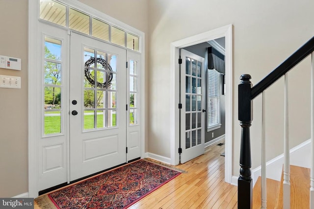 entryway with light wood finished floors, stairs, and baseboards