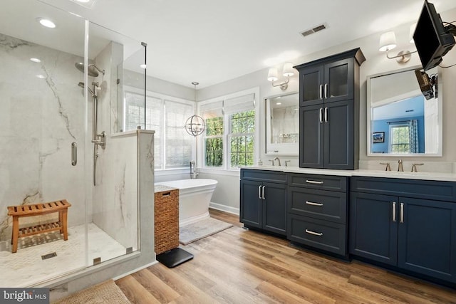 full bath with a marble finish shower, wood finished floors, a freestanding bath, and double vanity