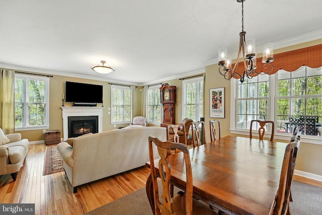 dining area featuring crown molding, healthy amount of natural light, a chandelier, and a glass covered fireplace