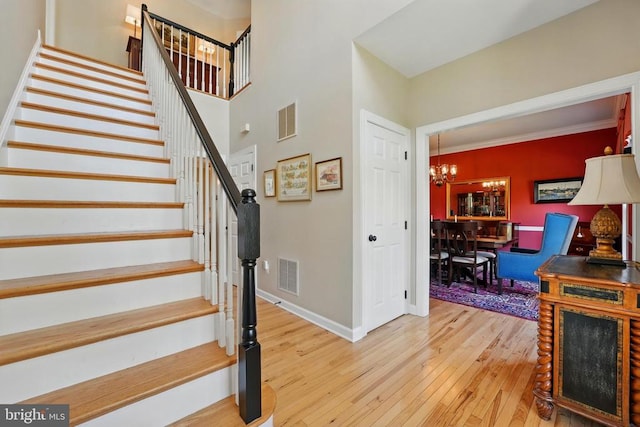 staircase with a chandelier, hardwood / wood-style flooring, and baseboards