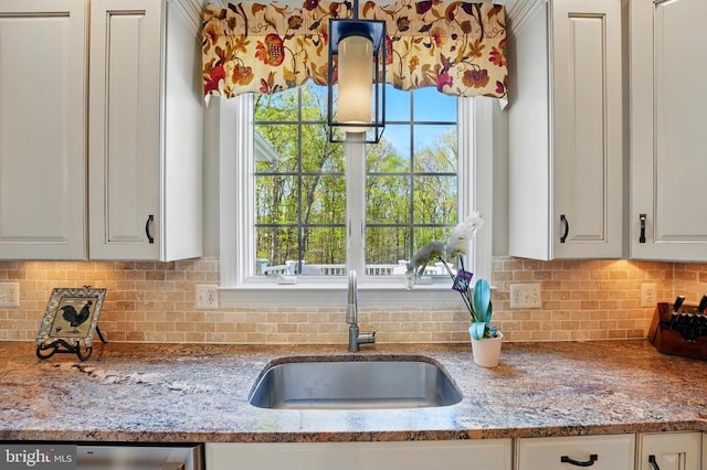 kitchen featuring a sink, decorative backsplash, light stone countertops, white cabinets, and dishwashing machine