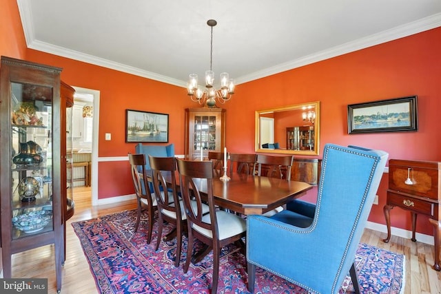 dining area with a chandelier, ornamental molding, wood finished floors, and baseboards