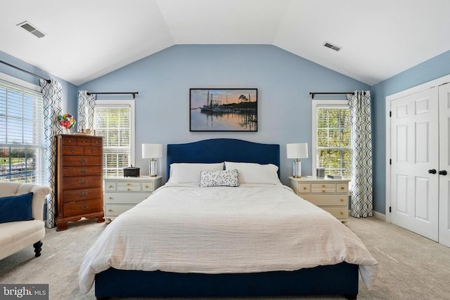 bedroom featuring light carpet, vaulted ceiling, and a closet