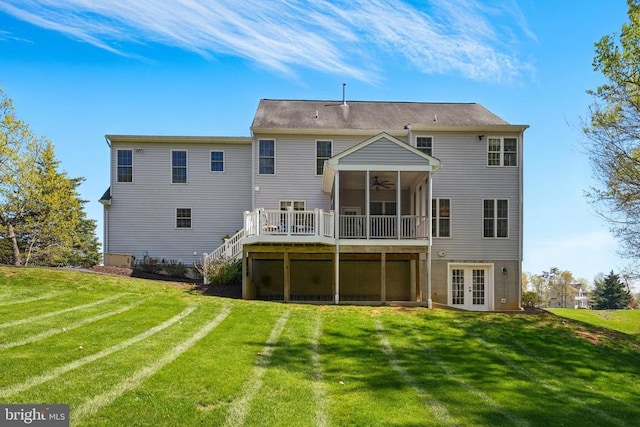 rear view of house with french doors, a ceiling fan, a wooden deck, and a lawn