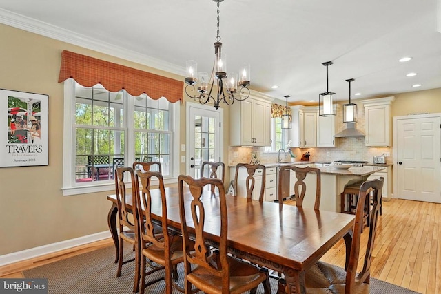 dining space with a chandelier, light wood finished floors, ornamental molding, recessed lighting, and baseboards