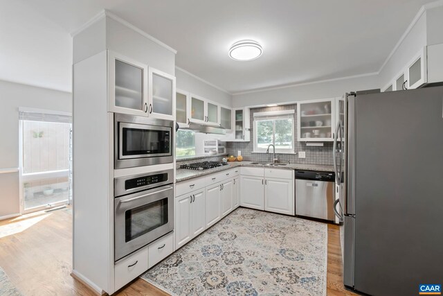 310 Gloucester Rd, Charlottesville, VA 22901 - kitchen featuring appliances with stainless steel finishes, light stone countertops, light wood finished floors, decorative backsplash, and crown molding