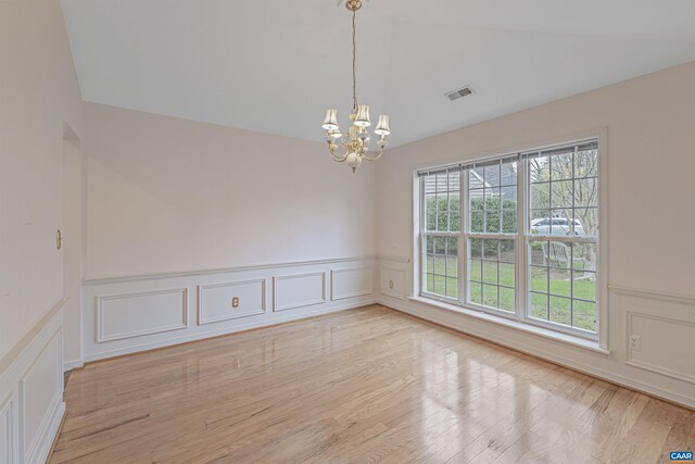 spare room featuring a decorative wall, a chandelier, and visible vents