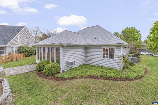 rear view of house featuring a yard, central air condition unit, roof with shingles, and fence