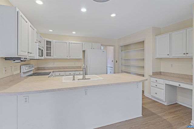 kitchen with a peninsula, light wood finished floors, glass insert cabinets, a sink, and white appliances