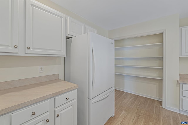 kitchen with freestanding refrigerator, light wood-style flooring, white cabinetry, and light countertops