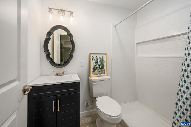 bathroom with toilet, tiled shower, and vanity