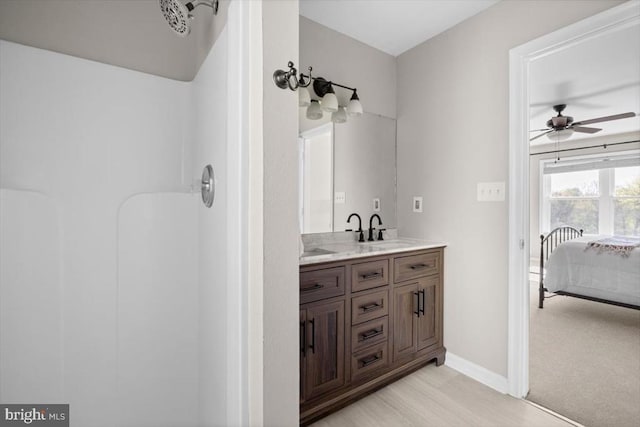 bathroom with a ceiling fan, double vanity, baseboards, a shower, and ensuite bathroom