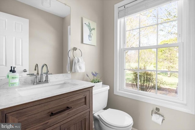 bathroom with toilet, vanity, and healthy amount of natural light
