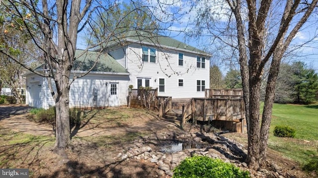rear view of property featuring an attached garage and a wooden deck