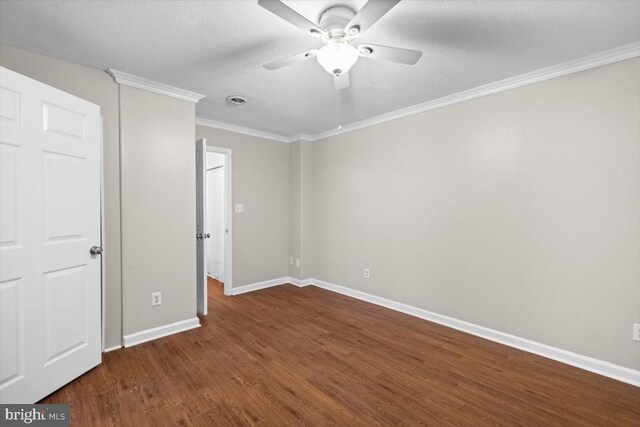 unfurnished bedroom with baseboards, dark wood-type flooring, ornamental molding, and a ceiling fan